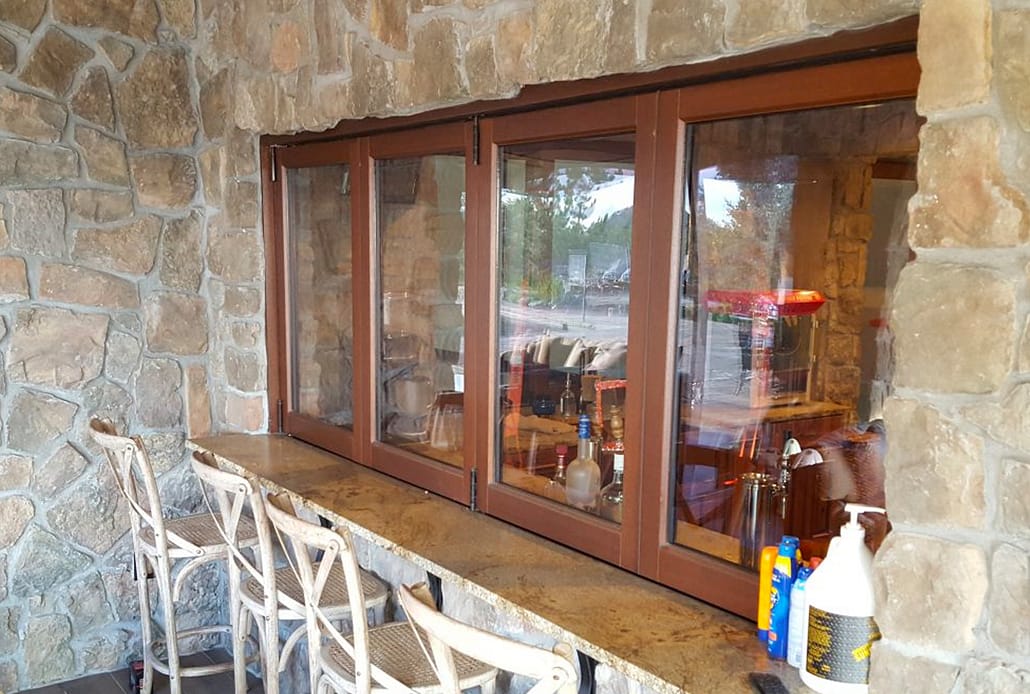 A custom four panel wood folding window allows access from the patio to the downstairs bar
