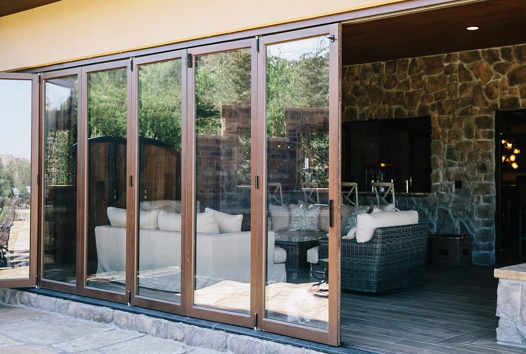 An eleven panel wood folding door system opens the downstairs living area to the pool and patio