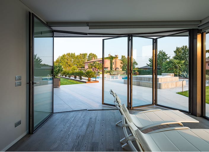 A thermally broken minimal frame folding steel doors open this pool house to the expansive outdoor pool