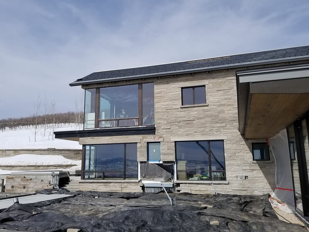 The installation of oversized steel windows is complete in this section of the expansive mountain retreat.