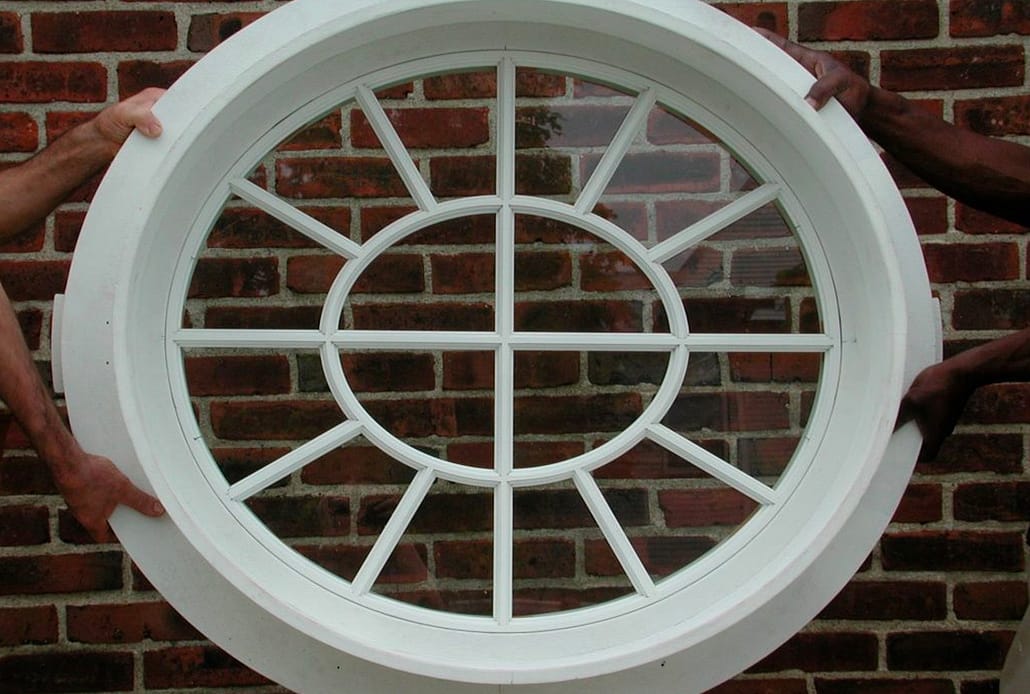 Install techs carry a historical restoration wood window into the house for placement