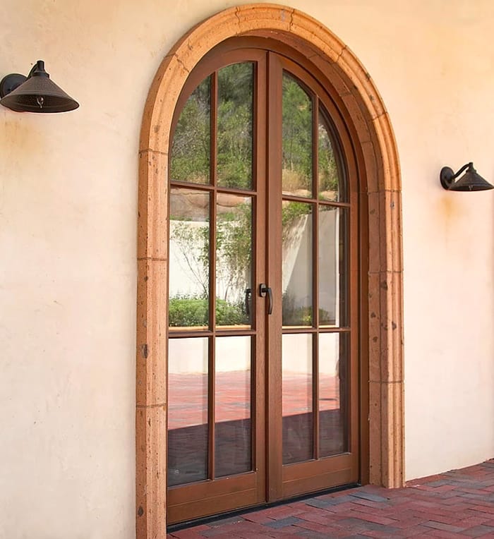 Entryways with a tuscan flair are seen here in this wood double entry door with narrow profiles