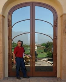 A 12 foot tall custom arched double wood entryway door with reflective glass