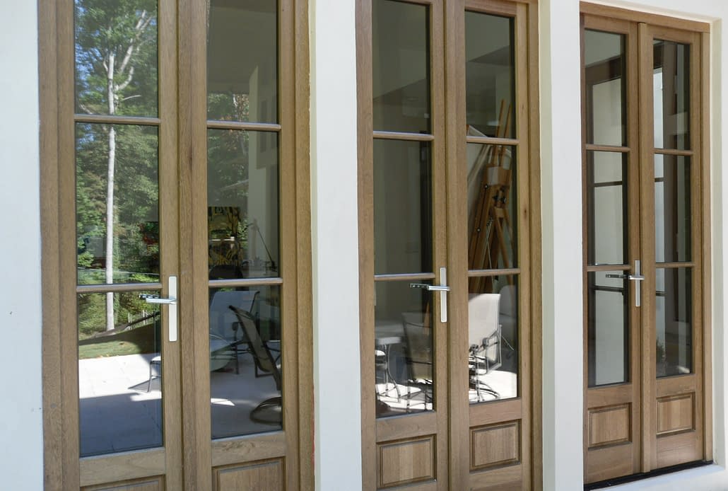 Three sets of custom wood inswing doors open the inside living space to the outdoor lounge