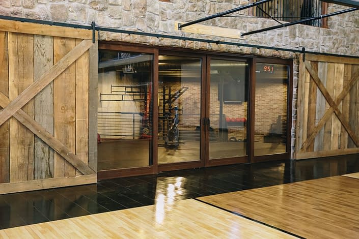 This custom wood lift slide door system separates the basketball court from the workout area