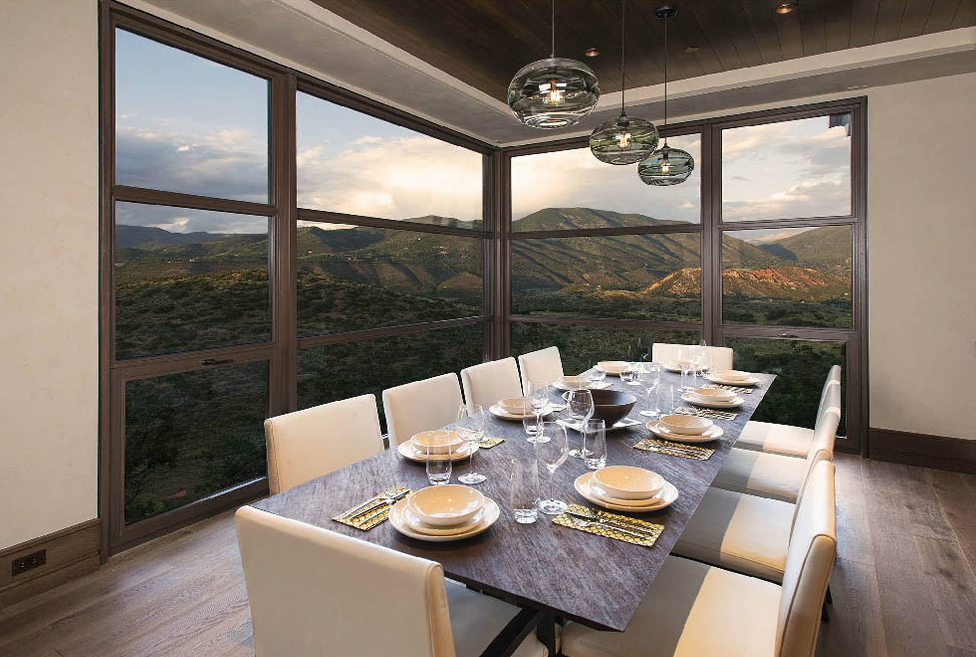 A dining room with a view through custom wood windows by Veranda View.