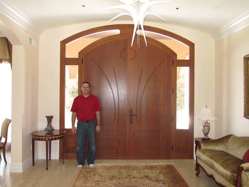 A custom arched double wood entryway door with dual sidelights and a transom by Veranda View
