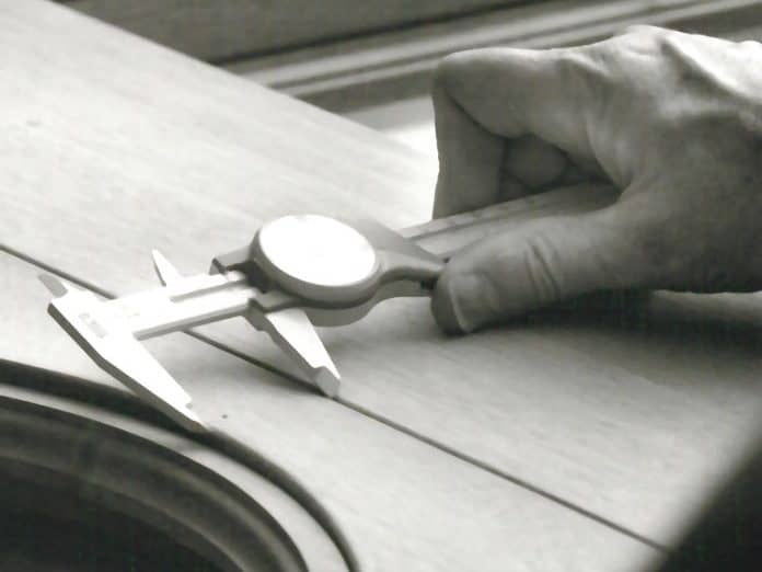 An individual performing measurements during the manufacturing of a custom wood window