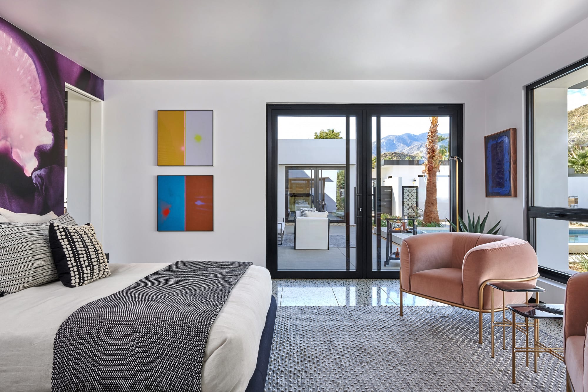 a pair of oversized aluminum pivot doors finished in black open the bedroom out to the pool area