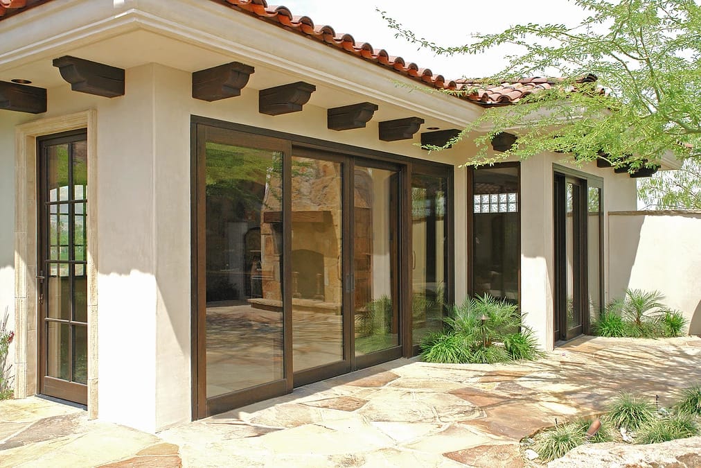 A tuscan style home with custom wood in swing doors, lift slide doors, and fixed windows by Veranda View