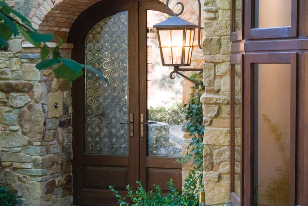 A custom European arched wood double entryway door with textured glass