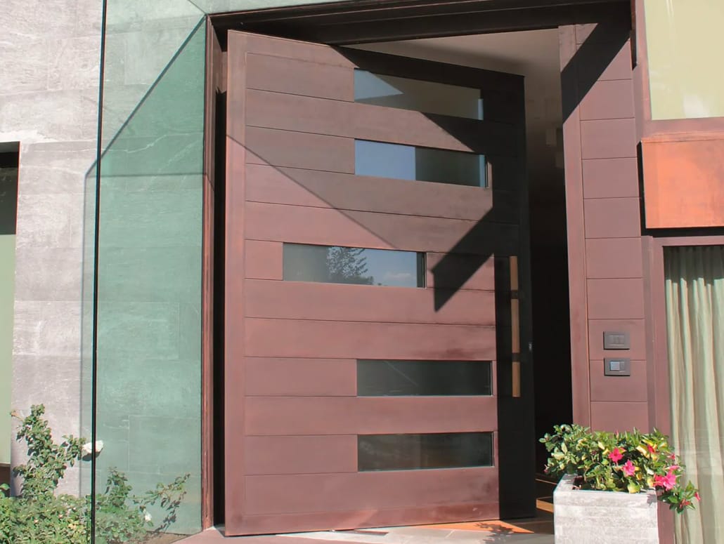 A wide pivot door in a cor-ten finish by Brombal sets the tone for the entrance of the house.