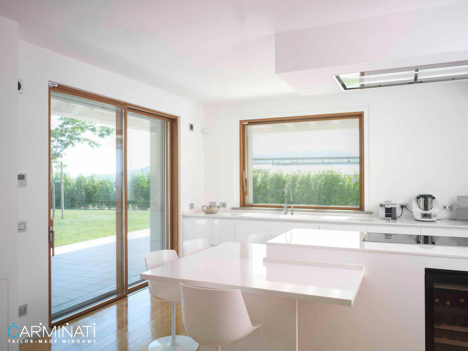 A modern kitchen complete with a minimal frame lift slide door and sliding window by Carminati